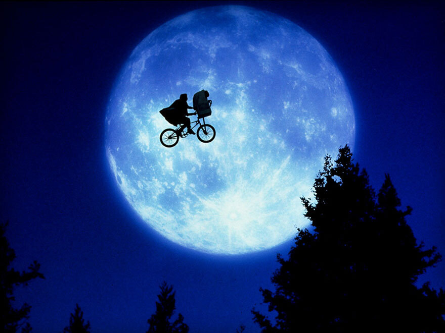 Cena do filme ET (1982): Bicicleta voando em frente a lua e a sombra de árvores abaixo