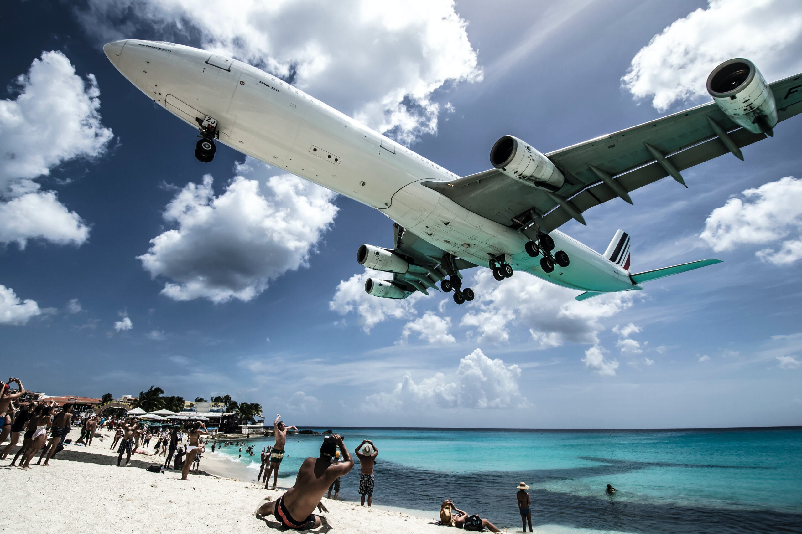 Aviões voam baixo, rente à praia, para aterrissar no aeroporto de Sint Maarten