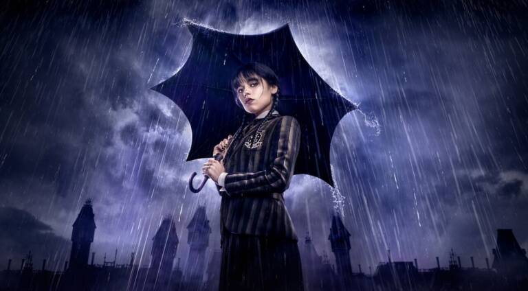 Foto mostra a atriz Jenna Ortega vestida de Wandinha Addams e segurando um guarda-chuva numa tempestade