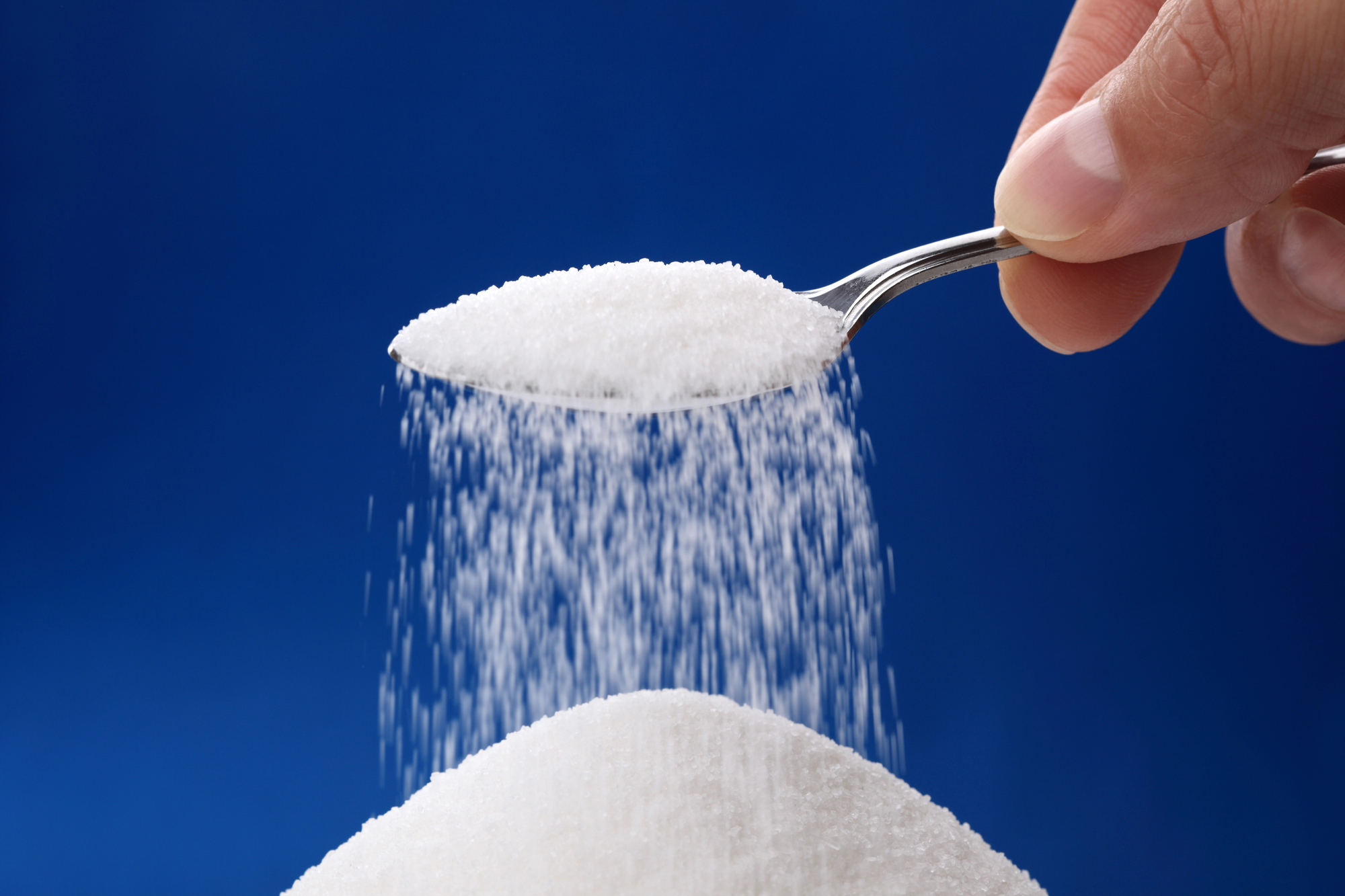 Colher com açúcar formando um monte do produto refinado
