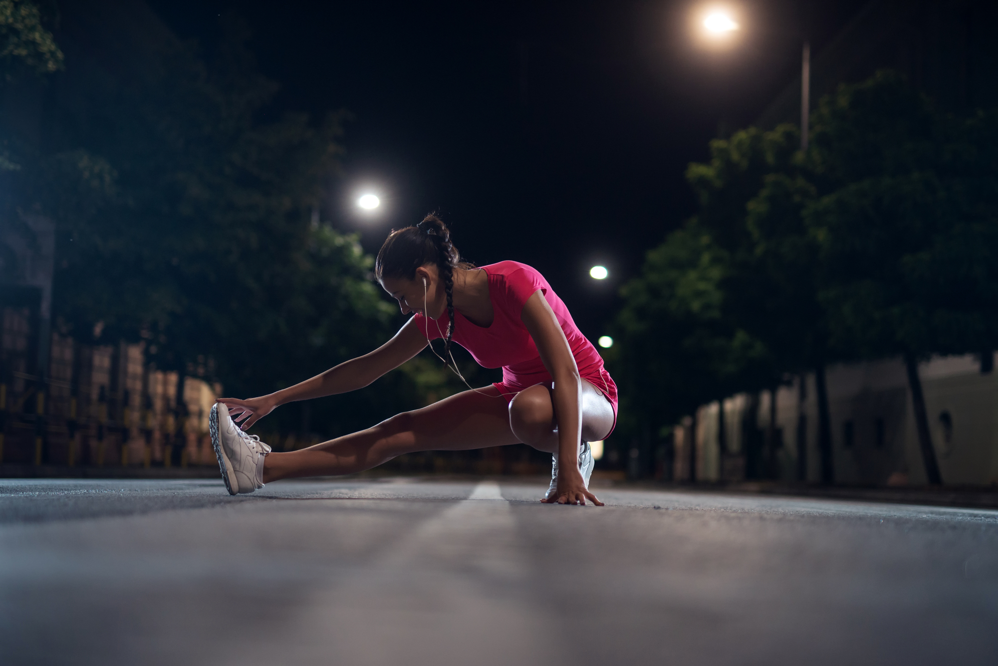 Mulher se alongando no meio da rua à noite prestar a começar exercício físico
