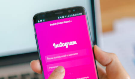 Foto mostra mão segurando celular com o Instagram aberto na tela de login