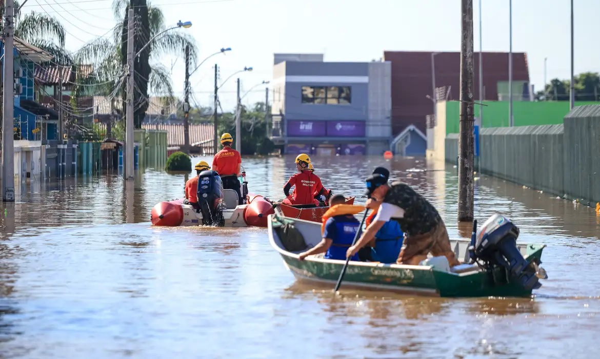 Pessoas sendo resgatas pelos bombeiros com canoas após enchentes no Rio Grande do Sul