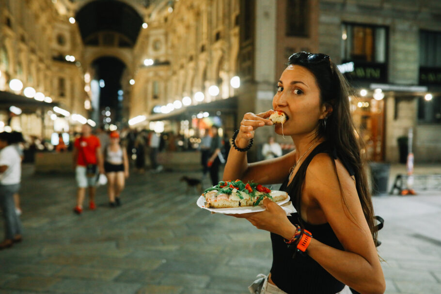 Turista come pizza em rua de Milão; cidade que proibir a venda do produto durante a madrugada