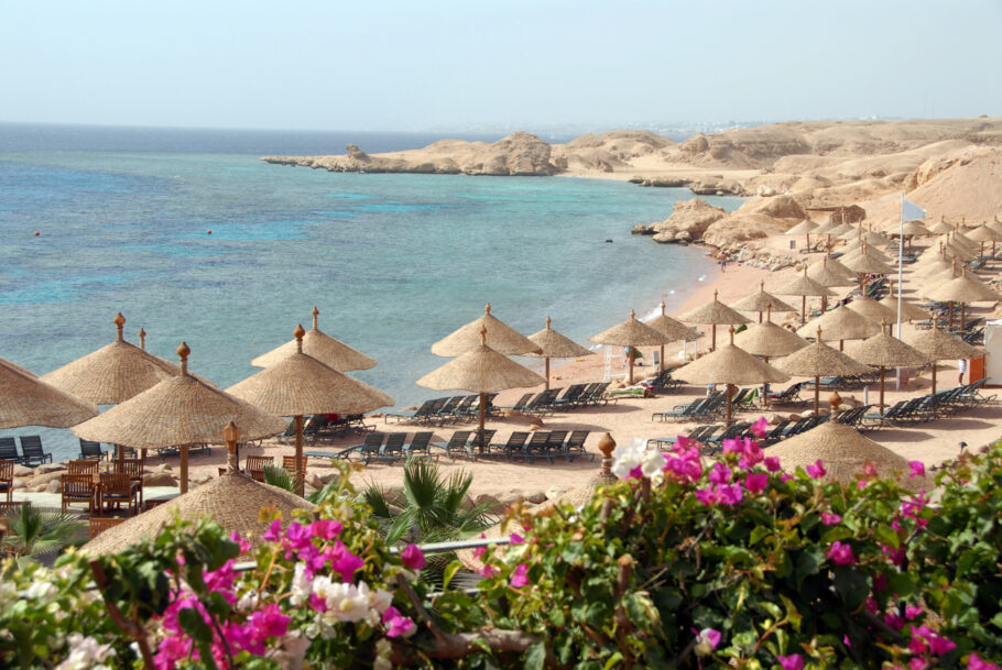 Praia com guarda-sóis e buganvílias floridas perto de Sharm el-Sheikh, Mar Vermelho, Egito.