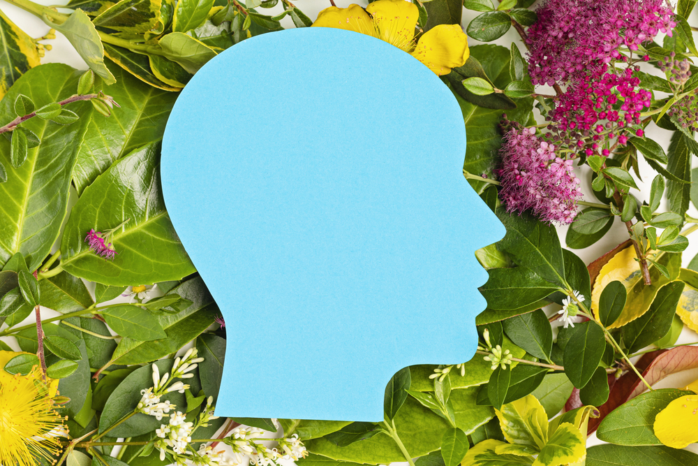 Papercut head with green leaves and flowers. Mental health, emotional wellness, contented emotions, self care, psychology, green thinking, ecology concept