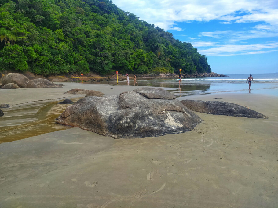 Alguns turistas aproveitando a praia de São Lourenço no início da manhã na Riviera de São Lourenço. Vegetação de mata atlântica, pedras de granito e o oceano Atlântico ao fundo. Fotografado na cidade de Bertioga, estado de São Paulo, Brasil.