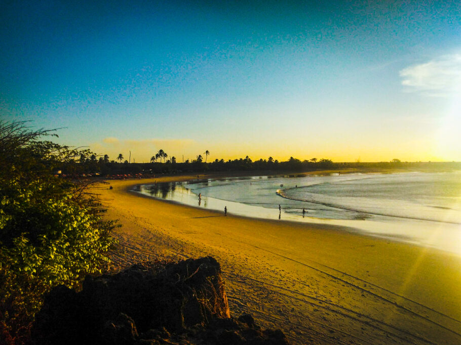 Fim de tarde onde os turistas se reúnem para ver o pôr do sol em uma duna. Abaixo você pode ver a beleza da praia e suas águas calmas.