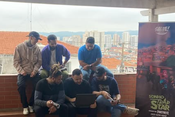 Equipe da Salve Games em ação: criadores do mapa Sonho TrapStar para Fortnite, projeto que conecta cultura urbana e games, discutem estratégias em um encontro com vista para a periferia que inspira suas criações.