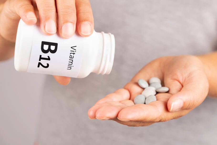 Woman hand takes vitamin B12 from medicine container