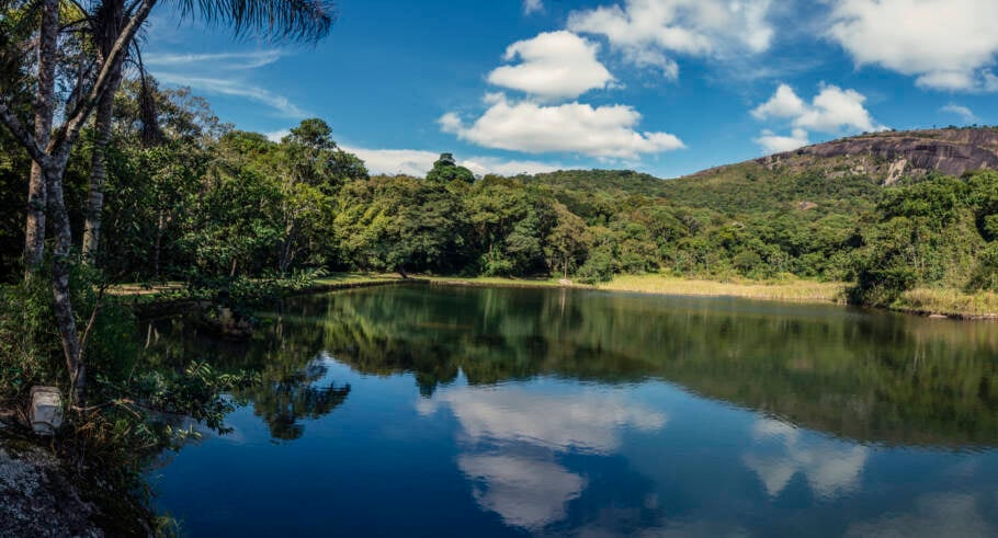 Panorama da paisagem natural com lago na Serra da Pedra Grande. Espelho d’água, vegetação local, montanha e céu azul com nuvens. Atibaia, São Paulo, Brasil.