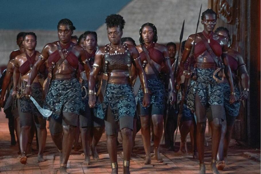 Cena de "A Mulher Rei" com guerreiras africanas marchando em formação com expressão séria