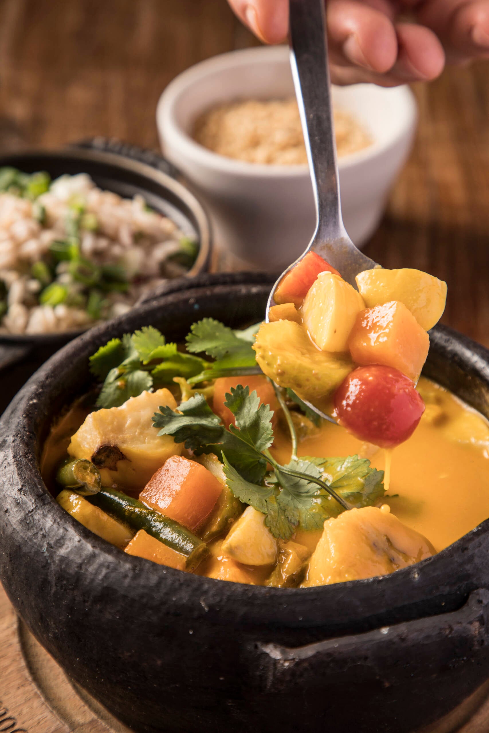 A Moqueca Sertaneja (R$94,90) mistura caju, banana-da-terra, maxixe, abóbora e folhas fresquinhas da horta, servida com arroz vermelho, farofa crocante de castanha e coco queimado