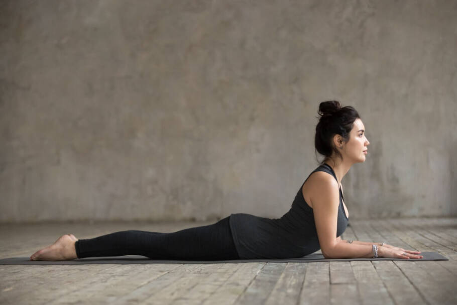 A bhujangasana postura ajuda a fortalecer a coluna e aliviar dores nas costas (Imagem: fizkes | Shutterstock)