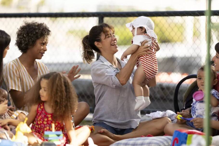 Atriz Miá Mello em um parque e segurando um bebê em cena de "Mãe Fora da Caixa"