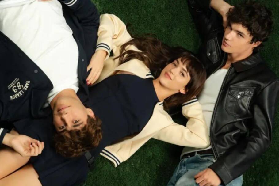 Capa do filme "Diga-me Baixinho" com uma mulher e dois homens deitados ao seu redor em uma grama verde