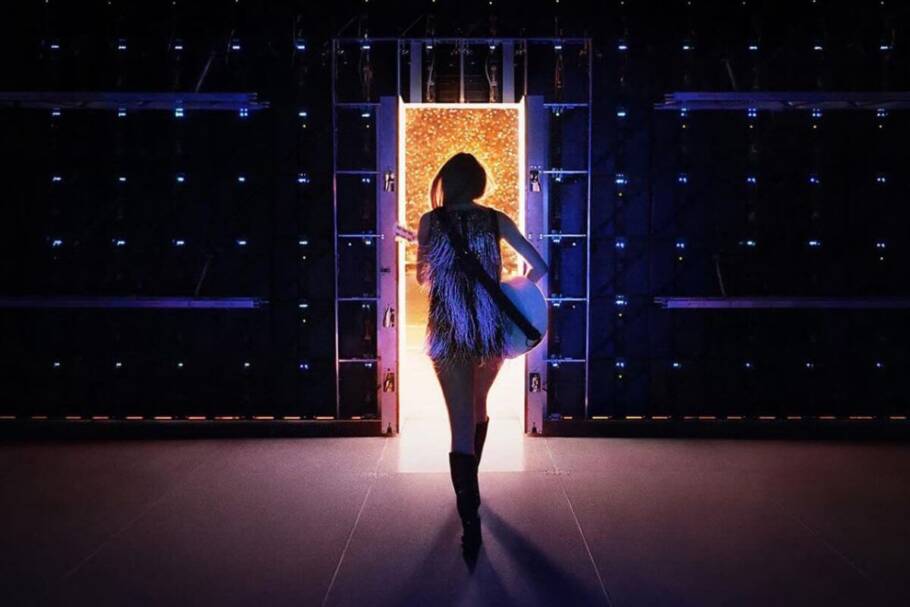Capa do "Taylor Swift: The End of an Era" com a cantora Taylor Swift segurando um violão e andando em direção a uma porta iluminada