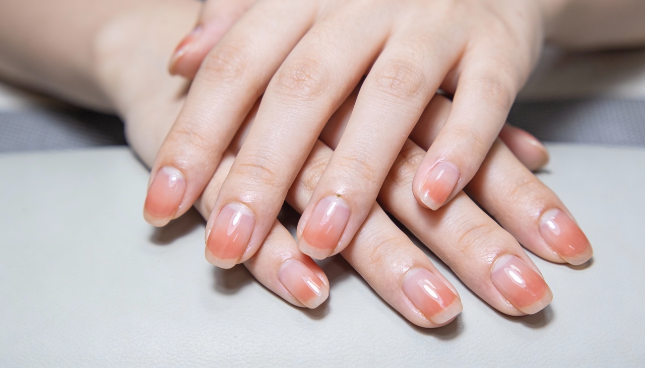 A cor do esmalte atua como um “filtro” visual, criando contraste ou harmonia com o tom de pele