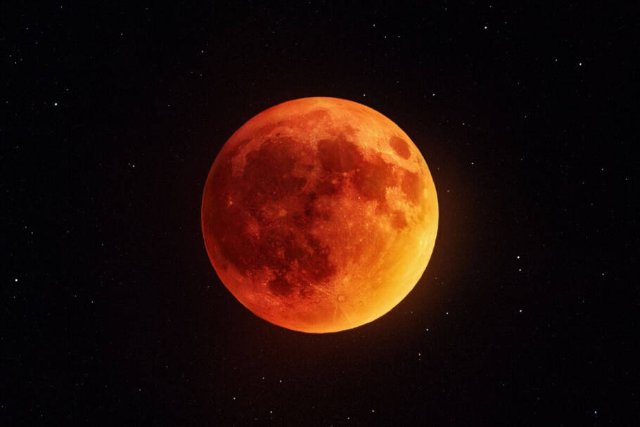 Fotografia centralizada da Lua cheia durante um eclipse lunar total, apresentando uma tonalidade avermelhada e alaranjada intensa, fenômeno conhecido como "Lua de Sangue".
