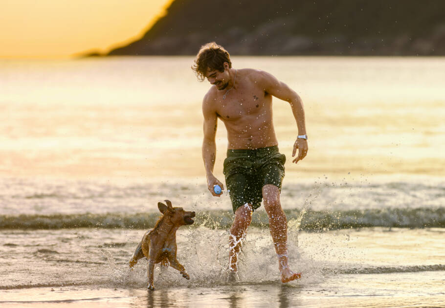 O ator Rafael Vitti e o cão Amendoim em cena do filme “Caramelo”, na Praia do Guaiúba, no Guarujá (SP)