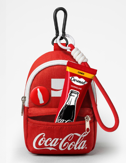 Espaço oferecerá ao público um brinde composto por uma mini bag charm e um hidratante labial da linha Carmed + Coca-Cola