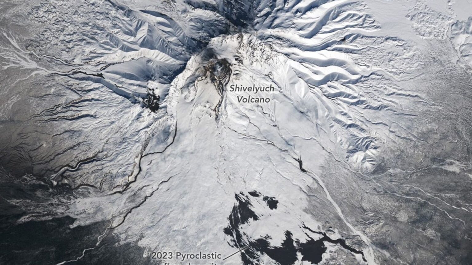 A imagem parece saída de um filme, mas é um registro real do espaço. Em 23 de abril de 2026, o satélite Landsat 9 fotografou o vulcão Shivelyuch na Península de Kamchatka, na Rússia, com neve perfurada por cicatrizes escuras descendo suas encostas.