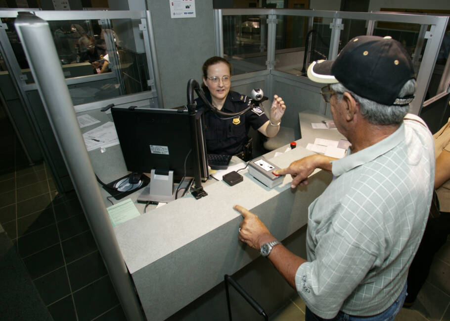 Agente da CBP usando um scanner para tirar foto de um viajante no controle de passaporte