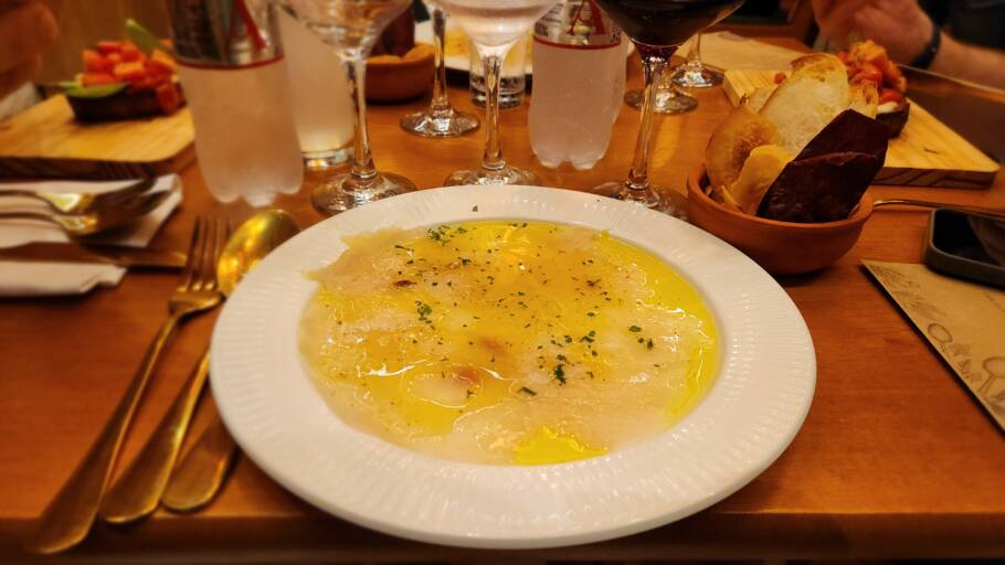 Carpaccio de pirarucu em finas fatias, flor de sal, raspas de limão-siciliano, brotos, azeite, chilli oil e alho roxo