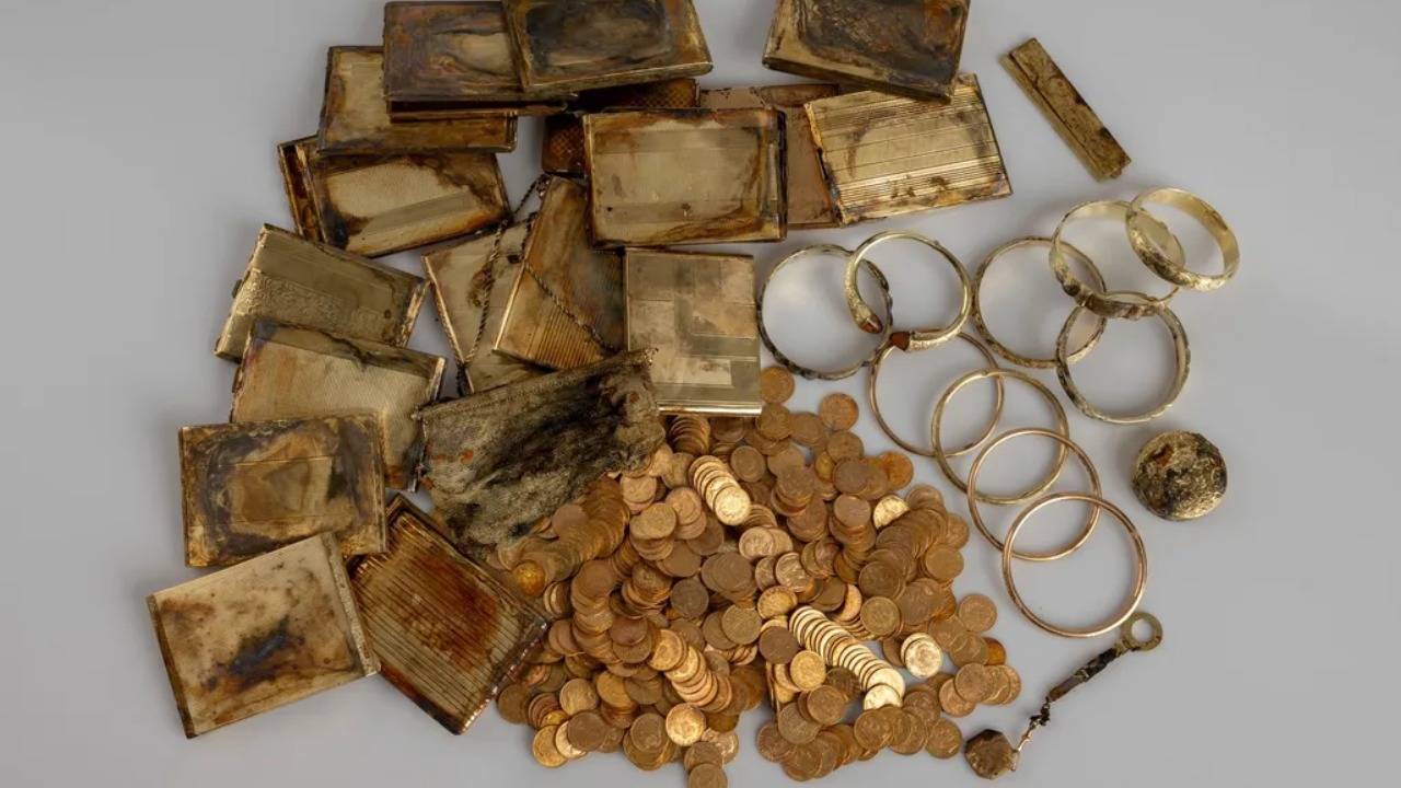 Recipiente de alumínio revelando moedas valiosas de várias nações cuidadosamente organizadas no solo.