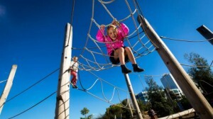 Menina se diverte em cordas de escalada do parque.