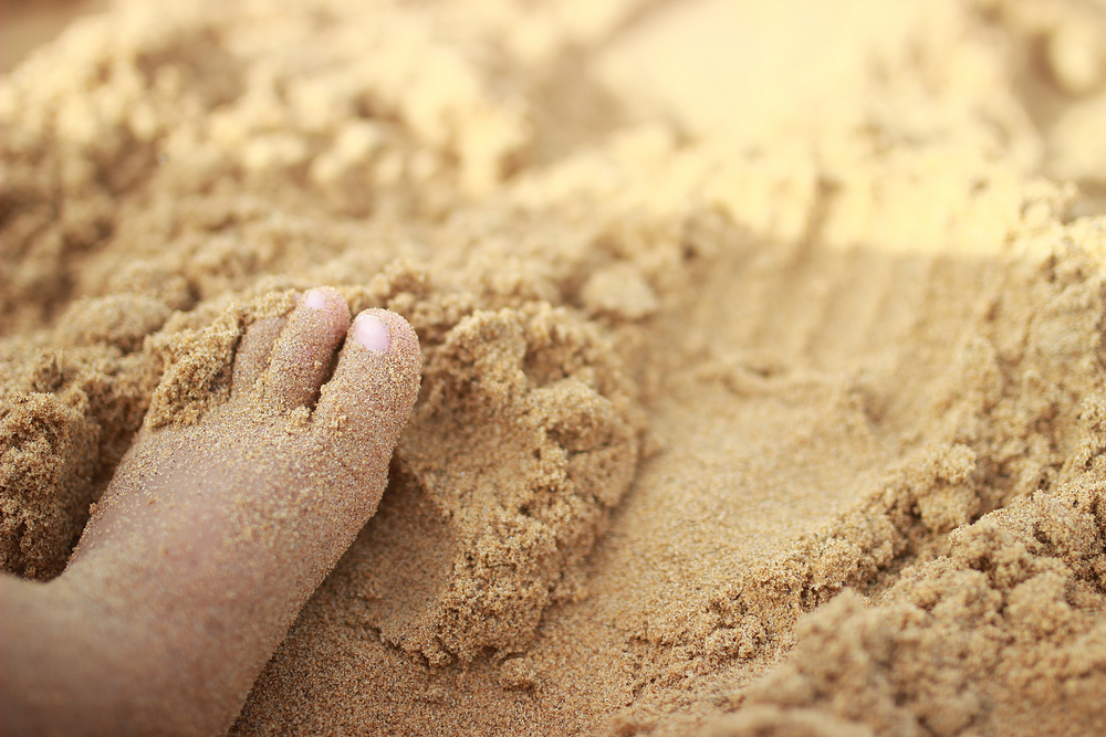 A areia massageia os pés da criança