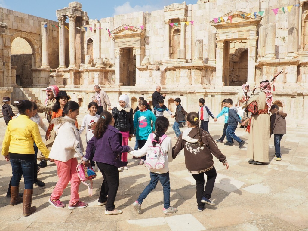 Crianças brincam próximas de ruínas romanas em Jerash, na Jordânia