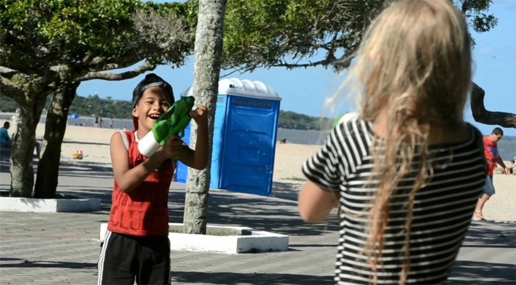 Crianças brincam de atirar protetor solar