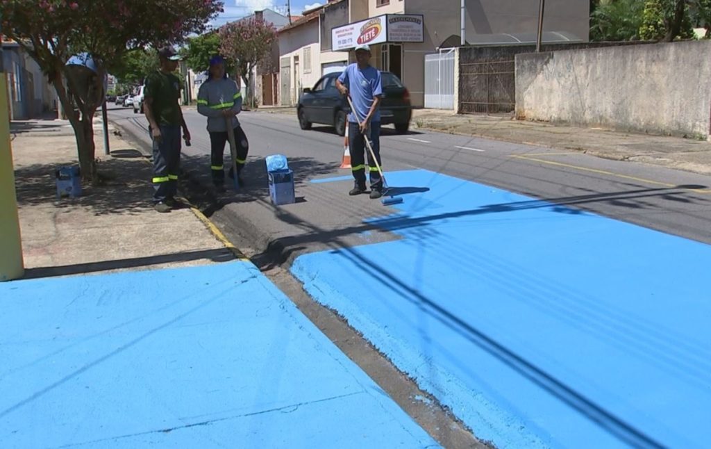 Funcionário da prefeitura de Tietê pintam rua de azul; ação é para diminuir a temperatura ambiente